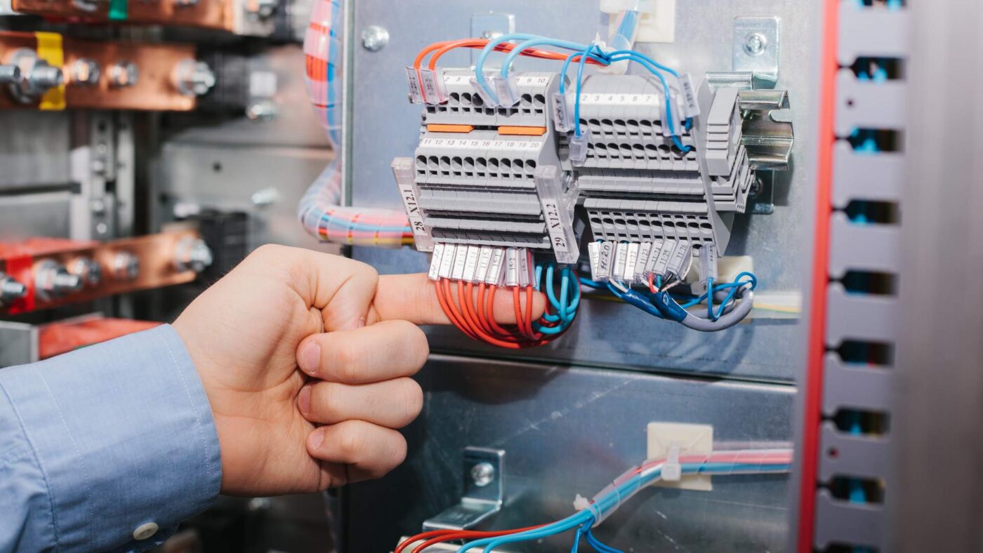 Una persona comprueba que las conexiones están bien realizadas en un cuadro eléctrico.